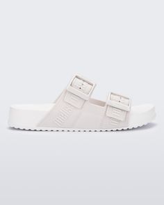 Side view of a white Cozy M Love adult slide Trendy Slides With Buckle Closure, Trendy Flat Heel Slides With Buckle Closure, Trendy White Footbed Sandals With Buckle Closure, Comfortable Flat Footbed Sandals With Buckle Closure, Casual Flat Footbed Sandals With Buckle Closure, Casual Sandals With Logo Strap For Spring, Casual Flat Footbed Sandals With Adjustable Straps, Casual Slide Footbed Sandals With Adjustable Straps, Cozy Chic