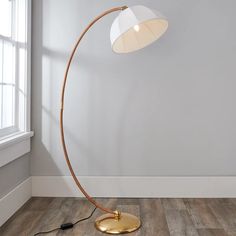 a floor lamp with a white shade on the top and a gold plated base