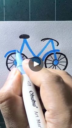 a person is drawing a bike on paper with blue marker and white crayon