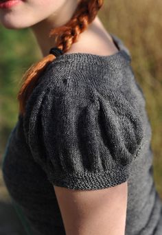 a woman with red hair wearing a gray sweater