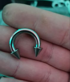 a person is holding a pair of silver colored metal piercings in their palm area