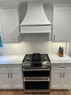 a stove top oven sitting inside of a kitchen next to white cabinets and counter tops