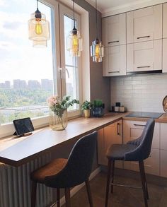 two chairs are sitting in front of a counter with a laptop on it and a window overlooking the city