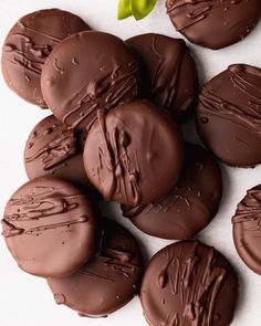 chocolate covered cookies sitting on top of a white surface next to a green leaf and flower