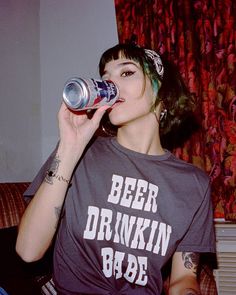 a woman sitting on a couch drinking from a can