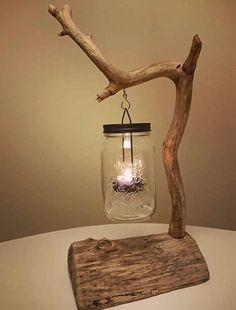 a candle in a jar hanging from a tree branch