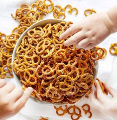 two hands reaching for pretzels in a bowl