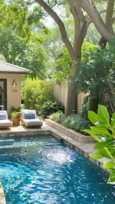 a small pool in the middle of a backyard with lounge chairs and trees around it