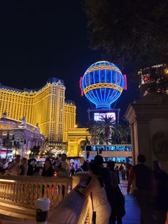 people are standing on a bridge in front of the las vegas hotel and casino at night