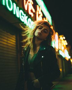 a woman standing in front of a neon sign