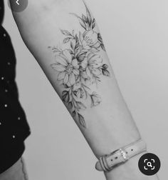 a black and white photo of a woman's arm with flowers tattooed on it