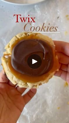 a person holding a chocolate covered doughnut in their hand with the words twix cookies on it