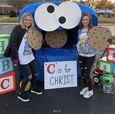 two girls are standing in front of a blue chair with a cookie monster on it