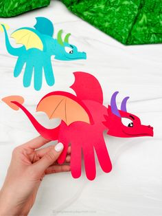 someone is holding up some paper cut outs to make a dragon and another one with wings