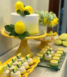 a table topped with yellow and white desserts next to lemon covered cakes on trays