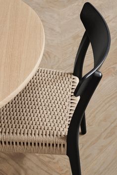 a close up of a wooden table with a black metal chair next to it on a hard wood floor