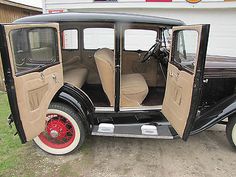 an old car is parked in front of a gas station with its door open and the driver's seat up