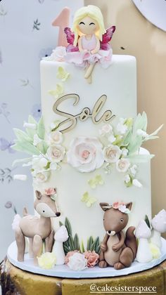 a white cake with pink flowers and angel figurines sitting on top of it