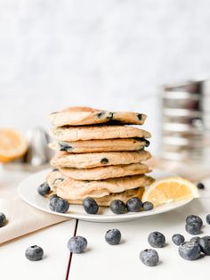 a stack of pancakes with blueberries and lemon slices