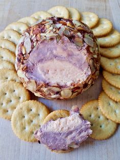 a cracker filled with cheese and nuts next to crackers on a wooden surface