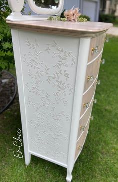 an old dresser is painted white and has flowers on it