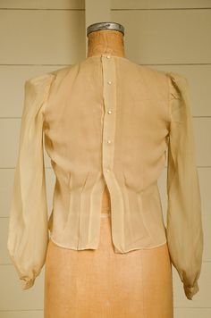 "Antique Silk Blouse Sheer Ivory Button Back Pleated Deco Blouse Beautiful silk blouse. Pleated front with a fitted waistline. Back has metal snap closures with pearl button coverings. Shows normal signs of wear. Measurements shoulders: 13 3/4'' chest: 36\" waist: 33\" length: 20\" sleeve: 23''" Formal Fitted Tops With Pearl Buttons, Classic Fitted Blouse With Pearl Buttons, Fitted Workwear Tops With Pearl Buttons, Fitted Tops With Pearl Buttons For Work, Formal Blouse With Pearl Buttons, Classic Formal Blouse With Pearl Buttons, Fitted Classic Blouse With Covered Buttons, Fitted Tops With Pearl Buttons, Classic Blouse With Pearl Buttons