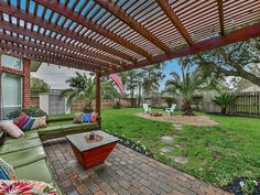 an outdoor living area with couches, tables and trees in the back yard on a sunny day