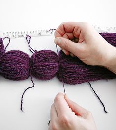 someone is knitting yarn on a table with a ruler