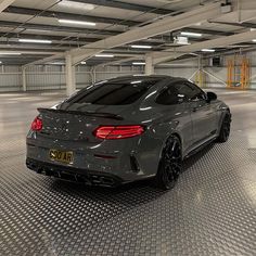 a grey sports car parked in a parking garage with no one on the ground around it