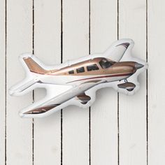 an airplane shaped magnet mounted to the side of a white wooden planked wall,