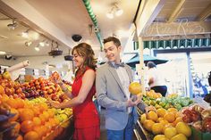 a man and woman standing next to each other at a fruit stand