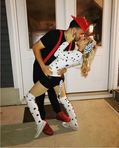 a man and woman dressed up as dalmatians kissing in front of a door