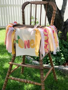 a wooden chair with a one sign on it and some ribbons hanging from the back