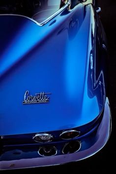 the front end of a blue sports car with its hood up and logo on it