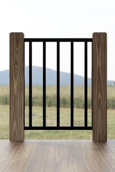 an open gate on top of a wooden floor in front of a field with mountains