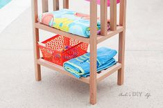 a wooden shelf with towels and other items on it next to a swimming pool area