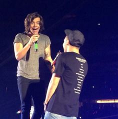 two men standing next to each other while holding microphones in their hands and laughing