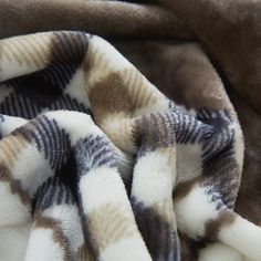 a brown and white blanket laying on top of a bed