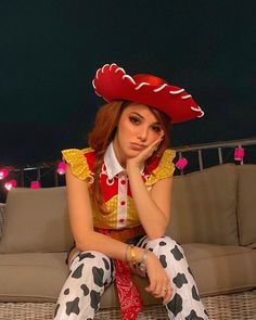 a woman sitting on top of a couch wearing cow print pants and a red hat