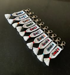 a row of white tasselled keychains with beads and crosses on them