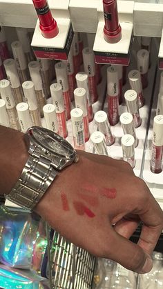 a person's hand with red lipstick on it in front of many different bottles