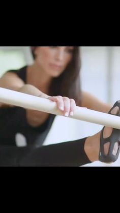 a woman is sitting on the ground with her arms crossed and holding onto a pole