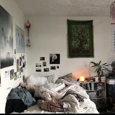 an unmade bed in a room with pictures on the wall