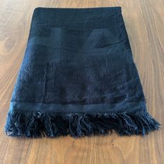 a black towel is laying on a wooden floor and it's fringed up