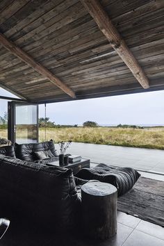 a living room with black leather furniture and large windows overlooking an open grassy field in the distance