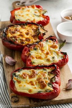 three stuffed red peppers on a cutting board