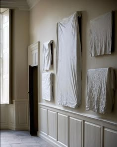 there are several pieces of cloth hanging on the wall in this room with white walls