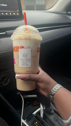 a woman holding up a drink in her car