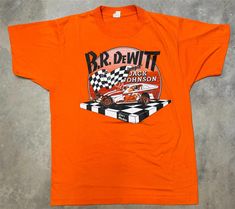 Rare! Vintage 1980s "Jumpin" Jack Johnson Big Block Dirt Modified Tee. Jack Johnson was an American dirt modified racing driver. A six-time Mr. Dirt Champion and four-time Super DIRT Series Champion, Johnson won 428 Modified feature races at 35 tracks in 10 states and two Canadian provinces. Jack Johnson was inducted into the New York State Stock Car Association and Eastern Motorsports Press Association Halls of Fame. Johnson was also nominated to the Northeast Dirt Modified Hall of Fame in 2002, but postponed his induction until 2012. This tee is in excellent conditon for its age, almost looks to be unworn.  Condition - 9/10 Used - Excellent Flaws: None Tagged - Large Fits: Medium Measures Pit to pit - 19" Collar to Bottom - 25.5" Condition is Used. Shipped with USPS First Class. American Dirt, Jack Johnson, Racing Driver, Walk Of Fame, Stock Car, Shop Fans, New York State, T-shirt, New York