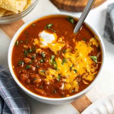 a bowl of chili with sour cream and tortilla chips